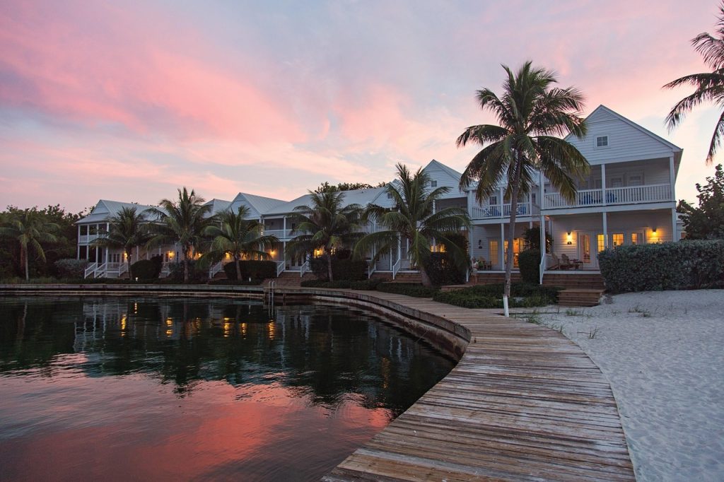 Waterfront resort cottages with palm trees reflecting at sunset
